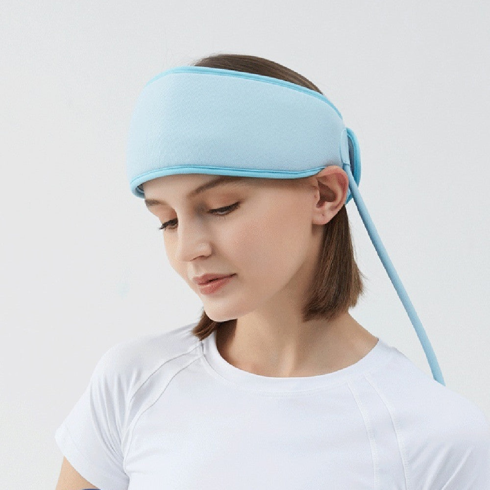 Woman wearing a light blue sleep mask on a plain background